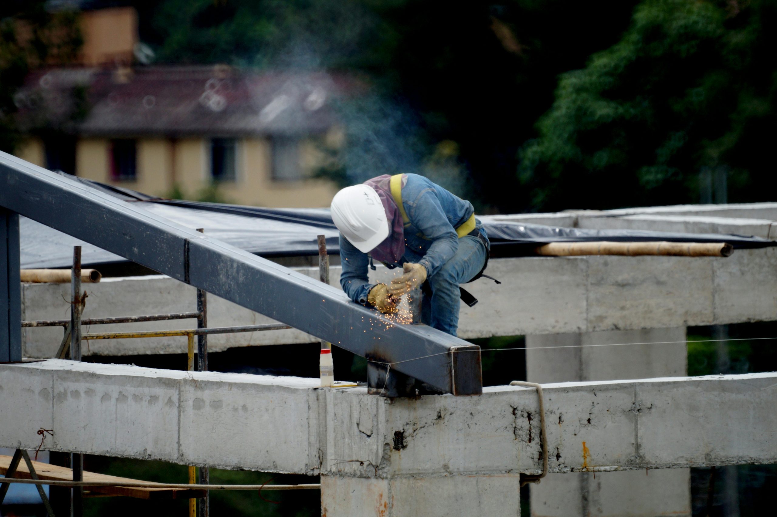 A construction worker welding steel beams on a building framework outdoors, ensuring structural safety.