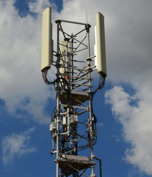 High-angle view of a modern cell tower with technology components against a blue sky with clouds.