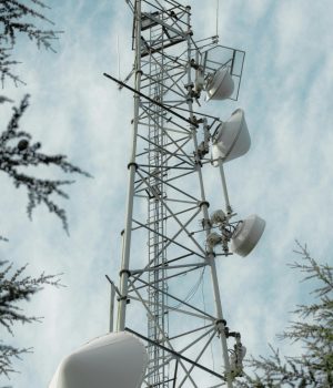 Aerial view of a tall telecommunication tower set against a blue sky with clouds.